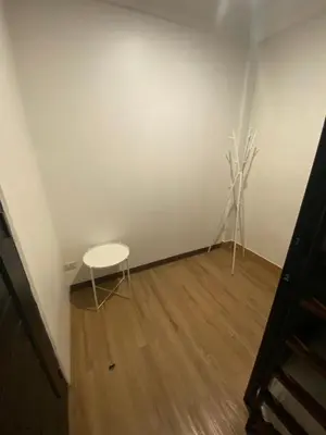 a white room with a white table and a wooden floor at Kudi Hostel in Bangkok