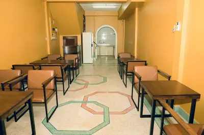 a dining room with tables and chairs and a refrigerator at Comfy Corner Hostel in Bangkok