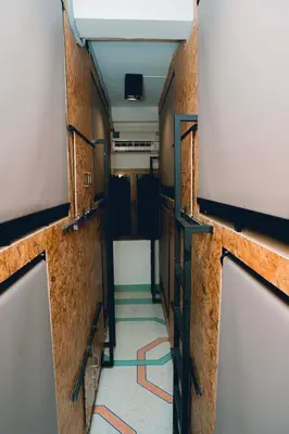 a corridor of a train with a hallway with orange wires at Comfy Corner Hostel in Bangkok