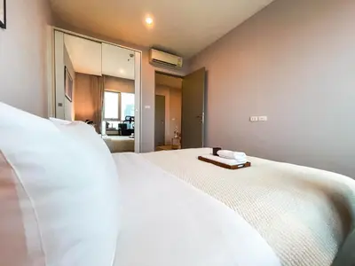 a bedroom with a large white bed with a mirror at Functional and comfortable-FastWiFi-MRT HuaiKhwang in Bangkok
