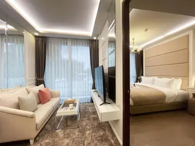 a hotel room with a bed and a couch and a television at Comfortable Stay 1BR - Ultra Fast Wifi - Huai Khwang in Bangkok