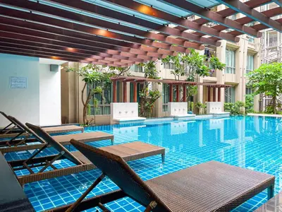 a swimming pool with tables and chairs in a building at Comfortable Stay 1BR - Ultra Fast Wifi - Huai Khwang in Bangkok