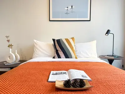 a bed with an orange blanket and a book on it at Expansive Luxury 2BR - Ultra Fast Wifi - Phrom Phong in Bangkok