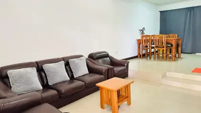 a living room with a brown couch and a table at Bangkok Halwa home in Sathani Ban Hua Mak