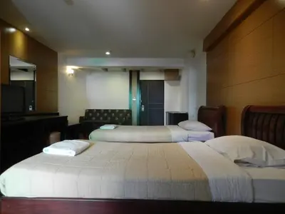 a hotel room with two beds and a television at Nanatai Suites in Bangkok