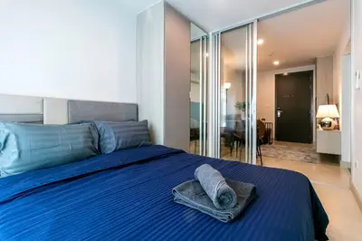 a bedroom with a blue bed with towels on it at TC Contel at Bts Samrong in Ban Khlong Samrong