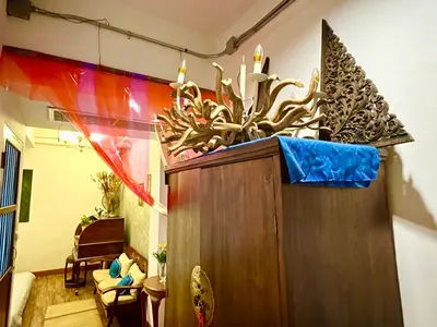 a large wooden cabinet in a room with a chair at WiNNiNE Cozy Home in Bangkok