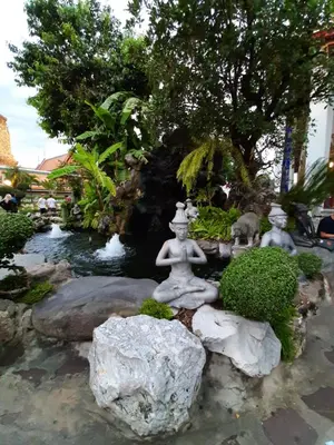 a garden with a statue in the middle of a pond at Chaiwat Guesthouse in Bangkok
