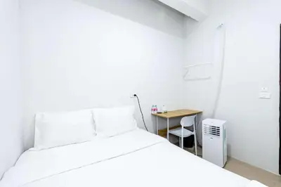 a white bedroom with a bed and a table at xx The Hidden Khaosan Road เดอะ ฮิดเด้น ถนนข้าวสาร - รามบุตรี in Bang Bua Thong Railway Station