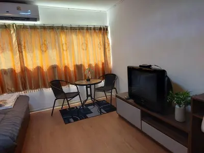 a living room with a tv and a table and chairs at Popular Muang Thong C5 in Thung Si Kan