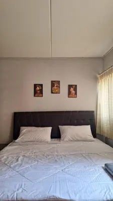 a bed in a bedroom with three pictures on the wall at Popular Muang Thong C5 in Thung Si Kan