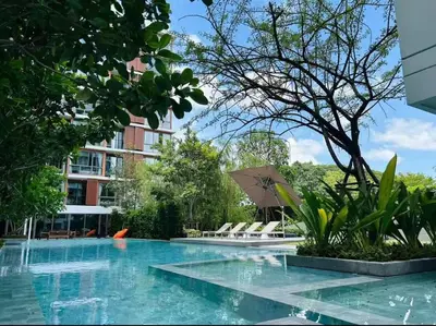 a pool with chairs and an umbrella next to a building at Thonglor Central Low rise Condominium in Bangkok