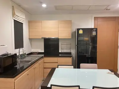 a kitchen with a black refrigerator and wooden cabinets at 'City Retreat' Asok Sukhumvit 23 Room 53 sqm in Bangkok
