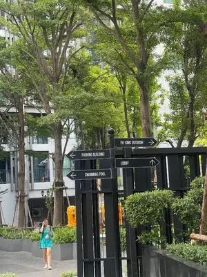 a woman in a blue dress walking past a street sign at Immaculate Quite Resort Home, brand new ACsWiFi in Amphoe Phra Khanong