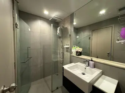 a bathroom with a sink and a shower and a mirror at Luxury Riverside condo in Nonthaburi