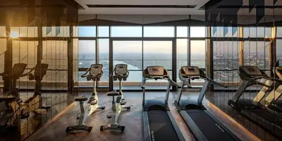a gym with four treadmills in front of a large window at Luxury Riverside condo in Nonthaburi