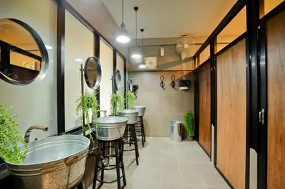 a bar with stools and a row of sinks and plants at Bangkok Bed and Bike in Bangkok