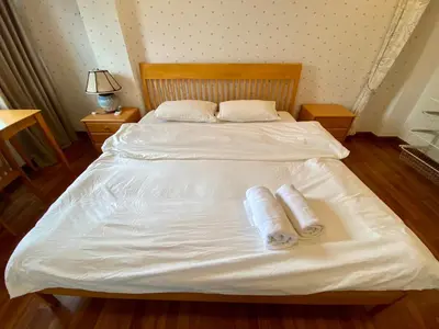 a large white bed with two rolled towels on it at ศรีย่าน เรสซิเดนซ์ Sriyan Residence in Dusit