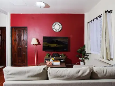 a living room with a couch and a red wall at Cozy House 2BR BTS Ekkamai in Bangkok