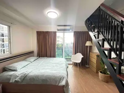 a bedroom with a bed and a spiral staircase at Modern 5-Bedroom Townhome near MRT and Local Charm in Bangkok