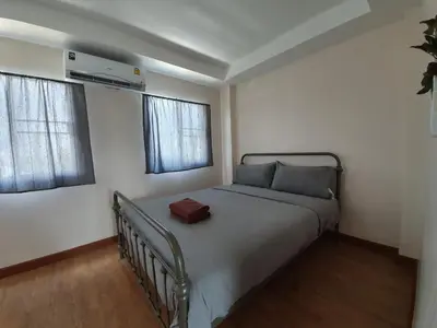 a bed in a room with two windows at Above Heaven - 4BR for 12 Pax near MRT Ratchadapisek in Bangkok