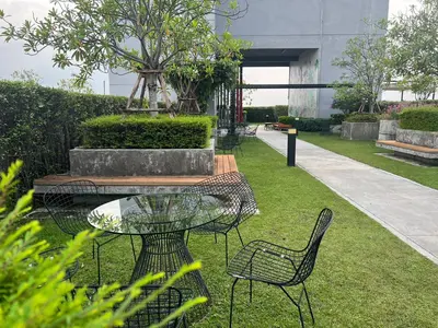 a patio with a table and chairs on the grass at Cozy9Living in Bangkok 60mto MRT in Ban Bang Khwang
