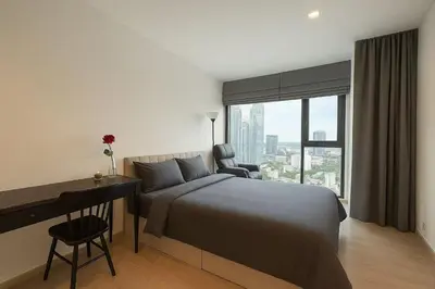 a bedroom with a bed and a desk and a window at BTS Thonglor Skyline Condo in Bangkok