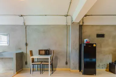 a kitchen with a table and a refrigerator in a room at Five Stars Residence in Bangkok