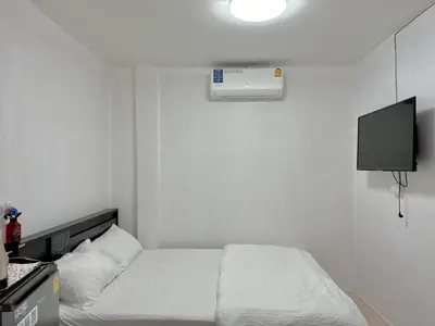 a white bedroom with a bed and a tv at Baan alisa 13 in Nonthaburi