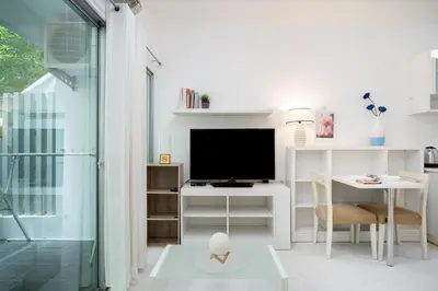 a living room with a tv and a desk with a computer at A space by cream in Bangkok