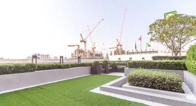 a garden with grass and bushes and cranes at Knightsbridge Duplex Tiwanon by Natcha in Nonthaburi