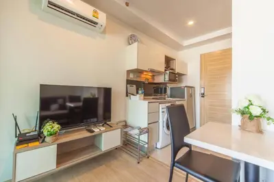 a living room with a large television and a table at Knightsbridge Duplex Tiwanon by Natcha in Nonthaburi