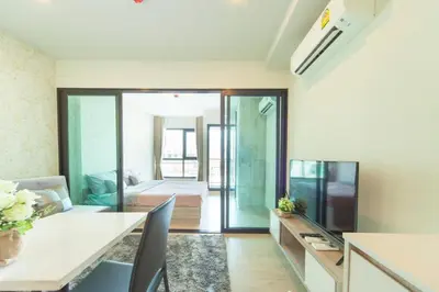 a living room with a dining table and a kitchen at Knightsbridge Duplex Tiwanon by Natcha in Nonthaburi