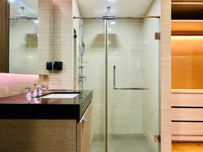 a bathroom with a glass shower and a sink at Klass Langsuan Condo in Bangkok