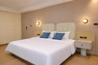 a bedroom with a large white bed with blue pillows at Ranana Bangkok in Bangkok