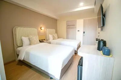 a hotel room with two beds and a television at Ranana Bangkok in Bangkok
