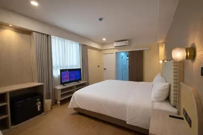 a bedroom with a white bed and a television at Ranana Bangkok in Bangkok