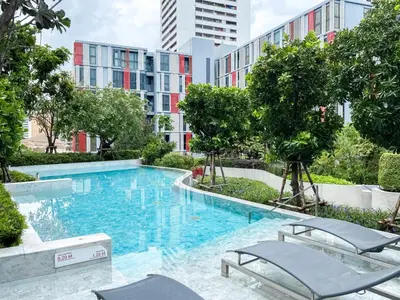 a swimming pool with chairs and trees in a building at Modern-Design Apt 45 sqm - Ultra Fast WiFi - Ekamai in Bangkok