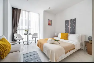 a bedroom with a large bed and a living room at Hyde Sukhumvit 11 Bankok in Bangkok
