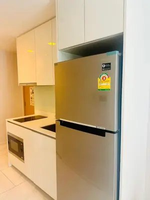 a kitchen with a stainless steel refrigerator and white cabinets at Hyde Sukhumvit 11 Bankok in Bangkok