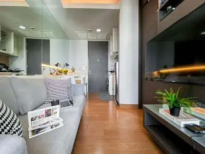 a living room with a couch and a large television at Upscale High-Rise 1BR - Ultra Fast Wifi - Phrom Phong in Bangkok