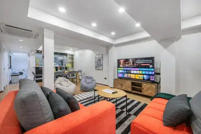 a living room with an orange couch and a flat screen tv at 4BR House For Family&Friends in Bangkok