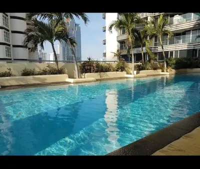 a large blue swimming pool with palm trees and buildings at Modern 59m Sukhumvit 1BR - 31st Floor Pool - Gym in Makkasan