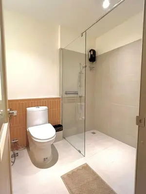a bathroom with a toilet and a glass shower at Slaap36 5BR Home with Parking, Walk to BTS Ari in Bangkok