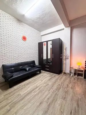 a living room with a black couch and a brick wall at Mango Rooms & Rooftop in Bangkok