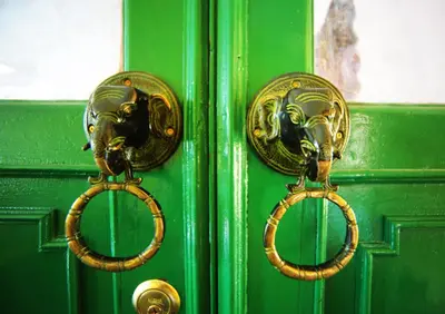 a green door with gold door knockers on it at The Myth - Sud Sathorn in Bangkok