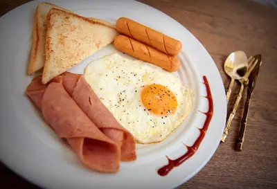 a plate of breakfast food with eggs ham and toast at The Myth - Sud Sathorn in Bangkok