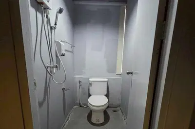 a small bathroom with a toilet and a shower at Sukhum Huai Khwang Guest House in Bangkok
