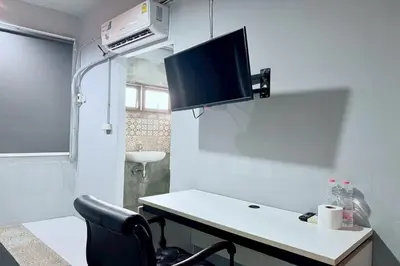 a room with a desk with a tv on the wall at Sukhum Huai Khwang Guest House in Bangkok