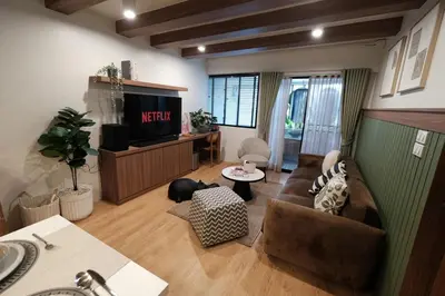 a living room with a couch and a tv at The Shantipan Lotus - Cozy 2BR Family Stay 400m from BTS Station in Bangkok